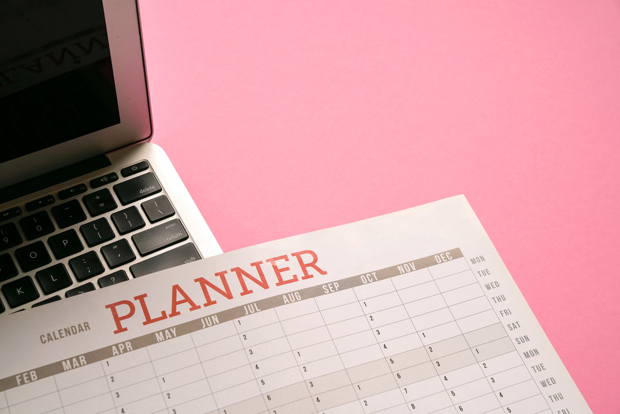 Calendar Planner and Computer Laptop on Top of Pink Table