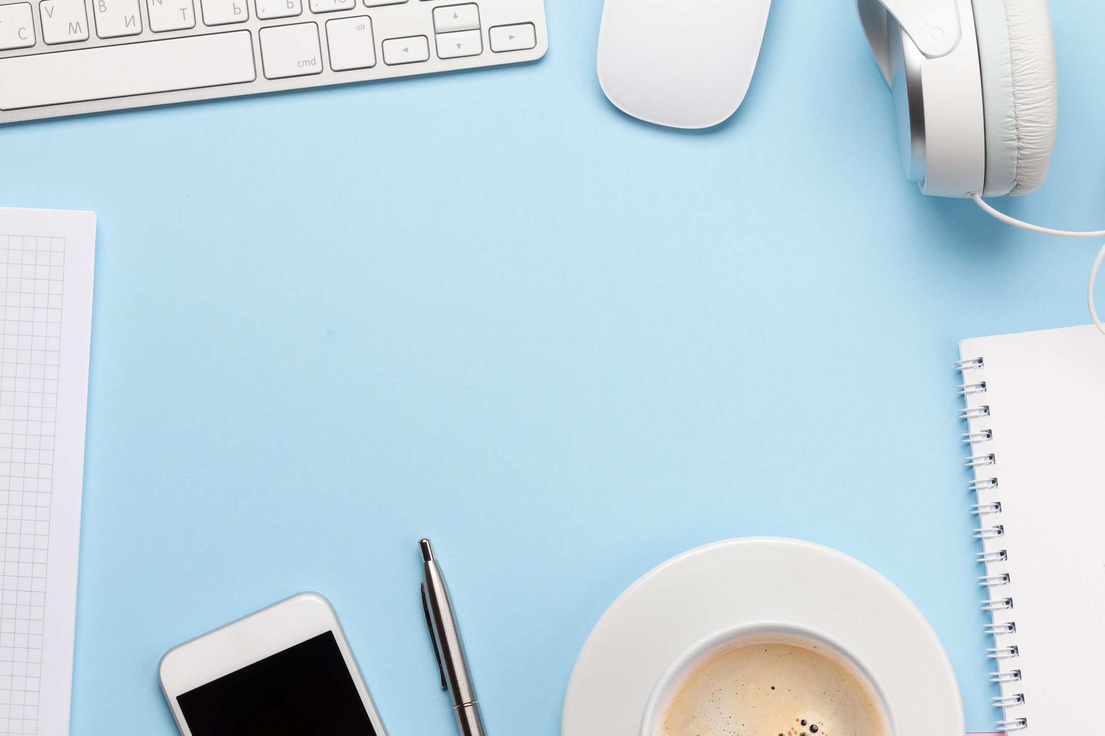 Blue desk with computer, smartphone, supplies and coffee